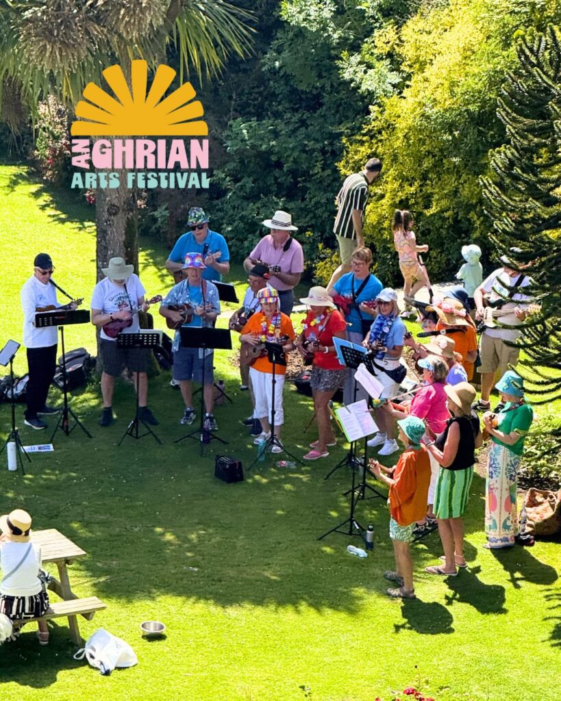 Skerries Ukulele Strummers playing on a green area under trees in the sunshine.